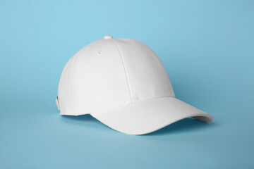 Stylish white baseball cap on light blue background