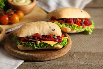 Delicious sandwiches with bresaola, lettuce and cheese on wooden table