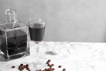 Coffee liqueur and beans on white marble table. Space for text