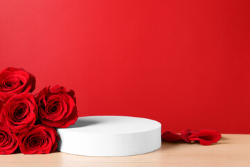 Stylish presentation for product. Round podium and beautiful roses on wooden table against red...