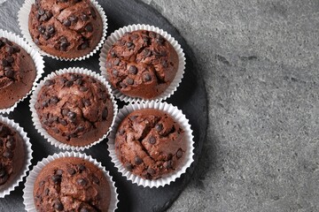 Tasty chocolate muffins on grey textured table, top view. Space for text