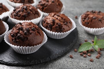 Tasty chocolate muffins on grey textured table, closeup