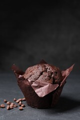 Tasty chocolate muffin on black textured table, closeup. Space for text