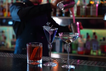Bartender making fresh alcoholic cocktail at counter in bar, selective focus