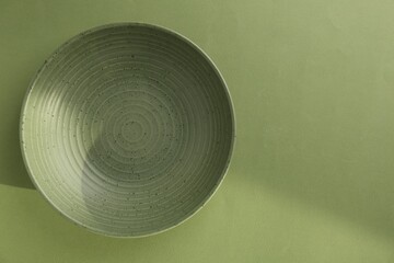 Beautiful ceramic bowl on green background, top view. Space for text