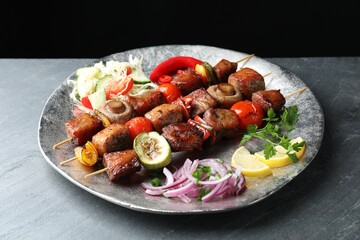 Delicious shish kebabs with vegetables on grey textured table, closeup