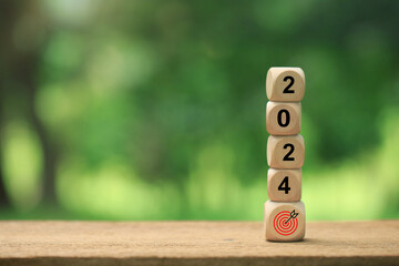 2024 Happy New Year background banner. Numbers on wooden cubes and target icon on the wooden cube....