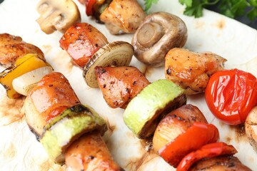 Delicious shish kebabs with mushroom, onion, tomato and zucchini on table, closeup