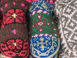 Multicolored wool knitted handmade mittens for the cold season. Things made of natural yarn. Winter clothes made of natural wool. Knitting with needles. Knitted fashion.