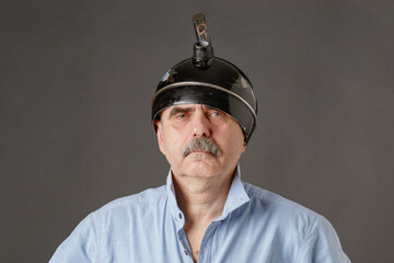 An eccentric man with a teapot on his head.