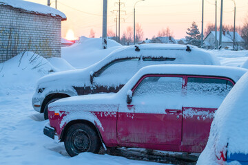 Old car under snow close up in winter.