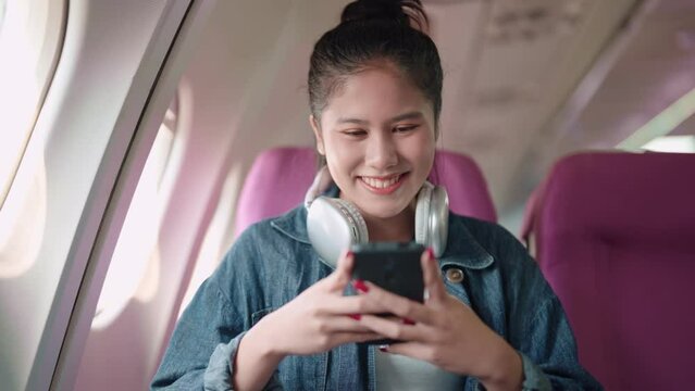 Asian businesswoman reviewing travel photos on her smartphone during a flight, combining work and leisure. Productive travels for successful meetings