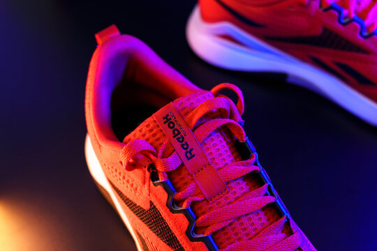 Tyumen, Russia-August 03, 2023: Red Reebok logo model Nanoflex sneakers, running shoes. Multicolored light. Selective focus