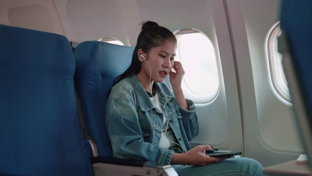 Asian female traveler enjoys her journey with headphones, playing music from her smartphone. Immerse in her travel playlist, blending the beats with the excitement of a long weekend getaway