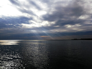 Fototapeta premium A view of the sea with light from the sun shining through the clouds and hitting the sea surface.