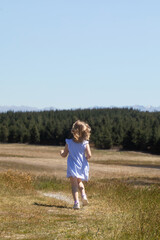 Cute funny girl running around the field in a dress in summer. Childhood, holidays.