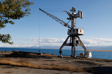 old abandoned soviet crane in Port Balykchy on Issyk-Kul lake at sunny autumn afternoon.