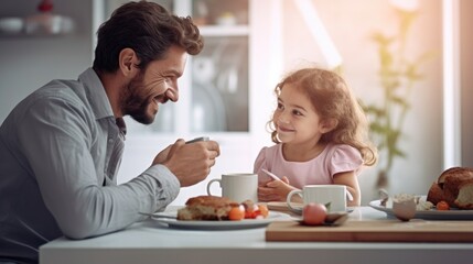 Fototapeta premium Handsome father with his little cute girl are having breakfast on kitchen. Happy Father's Day.