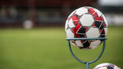 soccer ball in the storage rack holder with green grass and tribune in the background