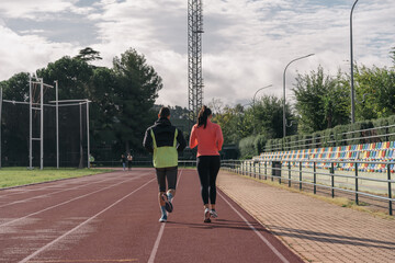 Young athletes crossing their arms due to the cold in the athletics track. Cold female and male athlete thinking whether to train athletics due to the low temperature in the morning smiling