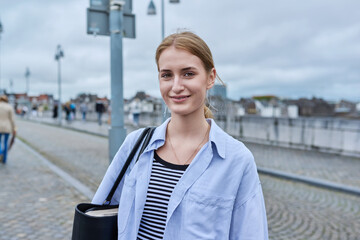 Young fashionable woman on bridge posing looking at camera, outdoor
