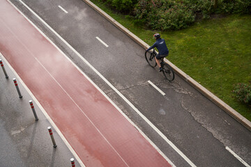 Obraz premium Man riding on bicycle on a bike path in the city. View from above.
