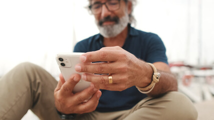 Close-up of the hands of an aged man holding mobile phone, the background is blurred