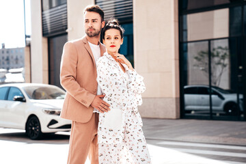 Beautiful fashion woman and her handsome elegant boyfriend in beige suit. Sexy brunette model in summer clothes. Fashionable smiling couple posing in street Europe. Brutal man and female outdoors