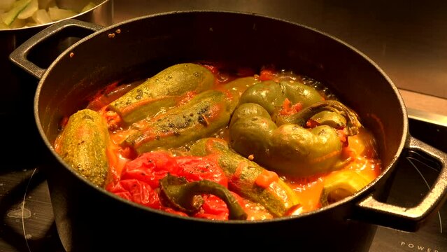 Whole mini courgettes and stuffed peppers cooking in a boiling dish. High quality 4k footage