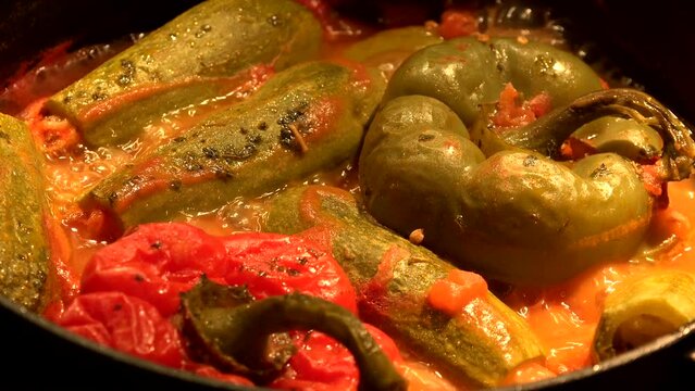 Whole mini courgettes and stuffed peppers cooking in a boiling dish. High quality 4k footage