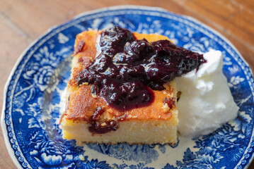 A slice of Malai, or alivenci, a cornbread-like cake from the Romanian cuisine, made with cornmeal and cheese, served with sour cream and blueberry jam