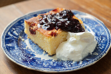 A slice of Malai, or alivenci, a cornbread-like cake from the Romanian cuisine, made with cornmeal and cheese, served with sour cream and blueberry jam