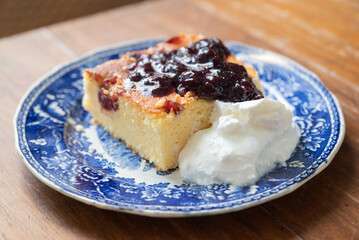 A slice of Malai, or alivenci, a cornbread-like cake from the Romanian cuisine, made with cornmeal and cheese, served with sour cream and blueberry jam