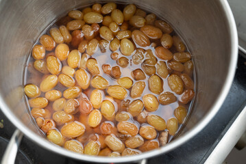 Grapes boiling in a pot with sugar, as part of the process of making homemade jam