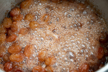 Grapes boiling in a pot with sugar, as part of the process of making homemade jam