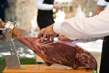 Manos de maestro jamonero cortando jamón en una fiesta.