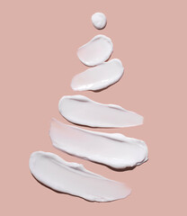 The concept of a Christmas tree in the form of cosmetic strokes on a pink background. Cream for...