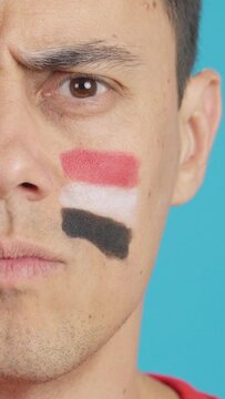 Serious man with a egyptian flag painted on the face