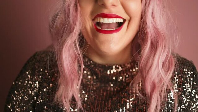 Cheerful beautiful girl wearing dress standing with red lips standing, celebrating isolated over pink background. High quality FullHD footage