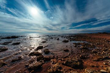 Rocky shore of lake in sunlight, wide angle view