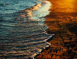 Sea coast with waves at sunset, close-up view