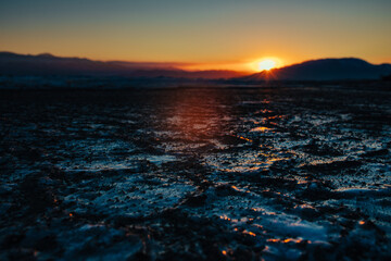 Dark ice on lake in cold winter weather, dramatic sunset light