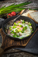 Fried eggs with ham on an old wooden background.