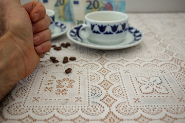 hand of a male, grains of coffee and cups of coffee and euro bills