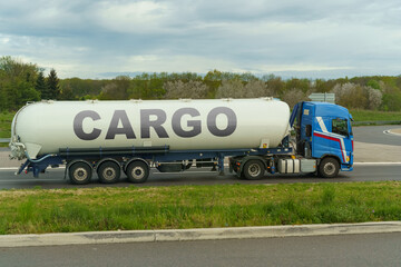 On a tank truck driving along the road there is an inscription - Cargo