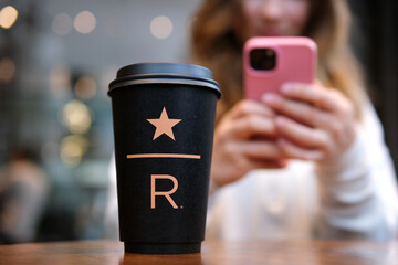 Starbucks Resort black Starbucks cup with star underline big letter R on the table in the coffee shop delicious new coffee luxury. famous brand newest