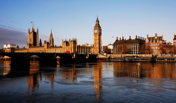 London skyline, peaceful morning tranquility, include many iconic landmarks such as Westminster Palace, Bridge, Victoria Tower, Thames River, Portcullis House and Water reflection present.