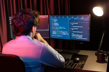 Working IT developer concentrating online software development information on surrounded by coding...