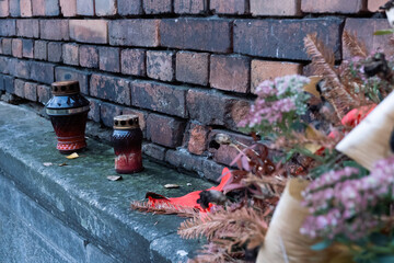 Grave candles and flowers on a stone wall