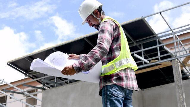 Middle-aged architect, foreman reading bluprint project paperwork standting against blue sky, engineering, small business Indian contractor male inspect unfinished real estate project workplace